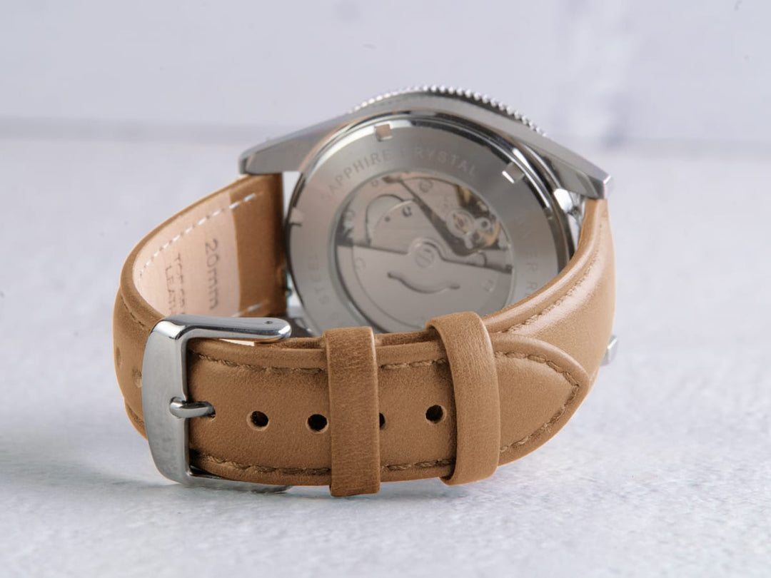 Back of a watch showing a tan leather quick-release strap with silver buckle